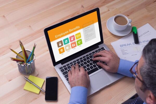 Man working on laptop with Employee Benefits on a screen